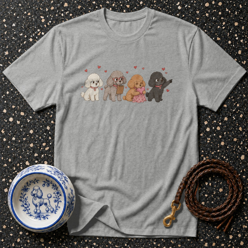 Grey t-shirt with a print of four poodles and red hearts, beside a dog bowl and leash.