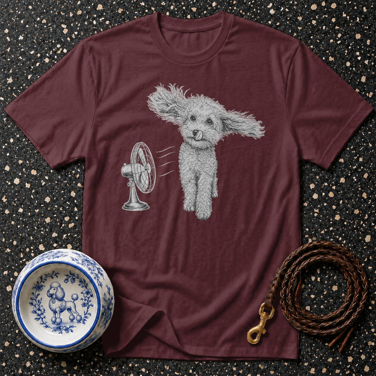 Maroon t-shirt with a drawing of a poodle enjoying a fan, a patterned dog bowl, and a leather leash.