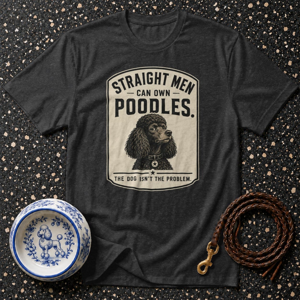 Dark grey t-shirt graphic with poodle illustration and "Straight men can own poodles. The dog isn't the problem." text.