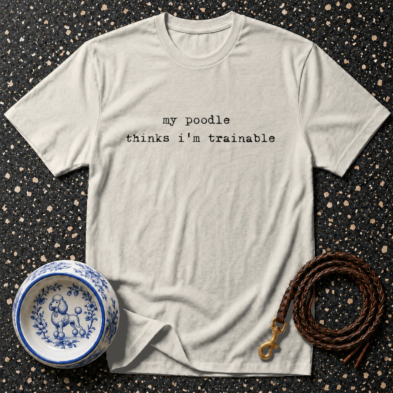 T-shirt with "my poodle thinks i'm trainable" text, dog bowl, and leash.