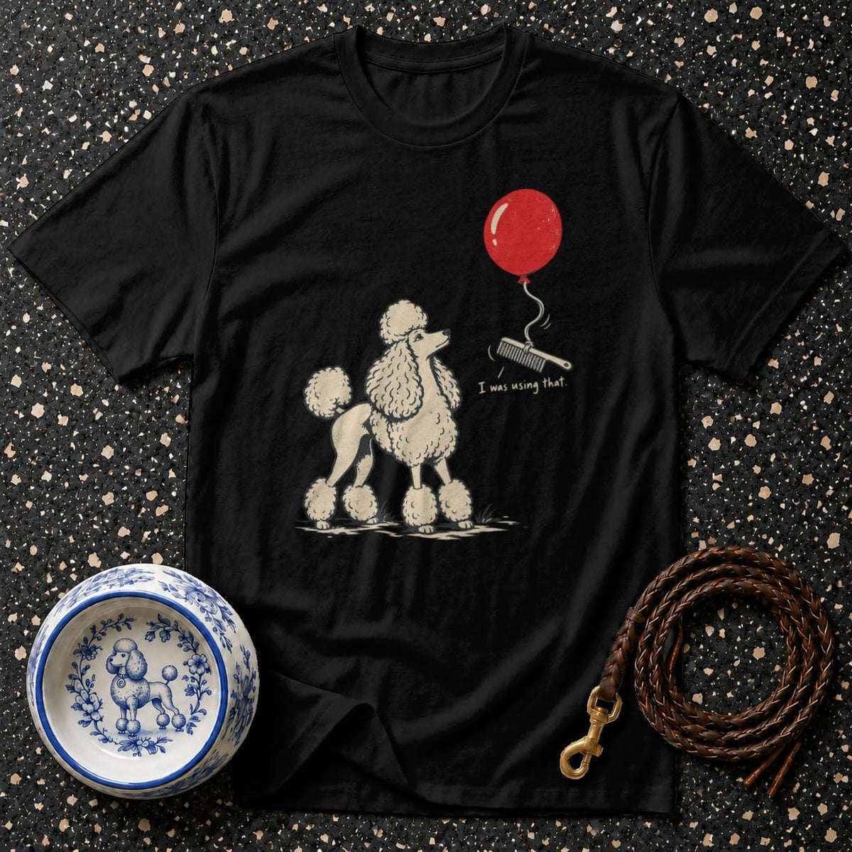 Black t-shirt with a poodle graphic, red balloon, comb, and text "I was using that."