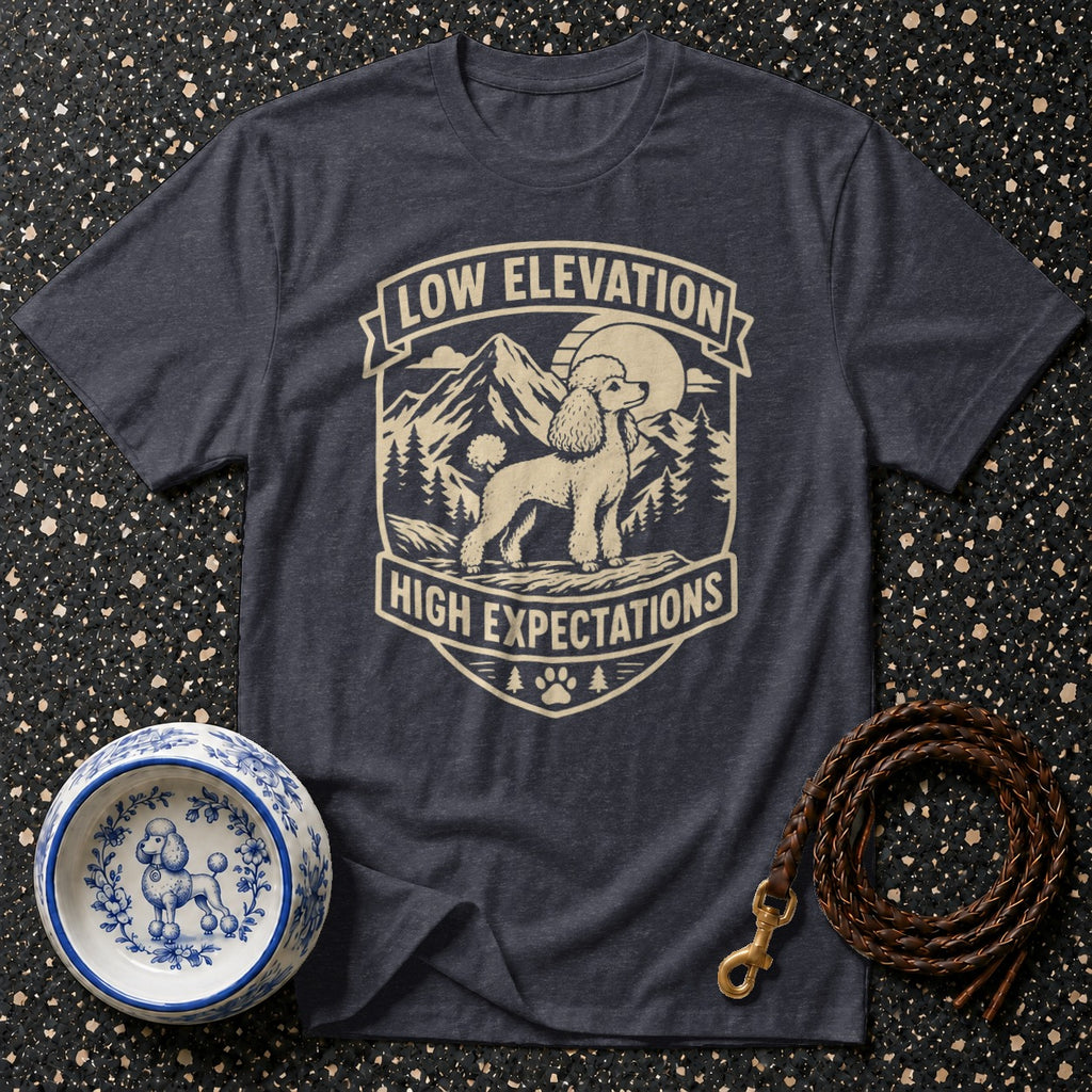 Dark t-shirt with a cream graphic of a poodle, mountains, and trees, text reads "Low Elevation High Expectations".