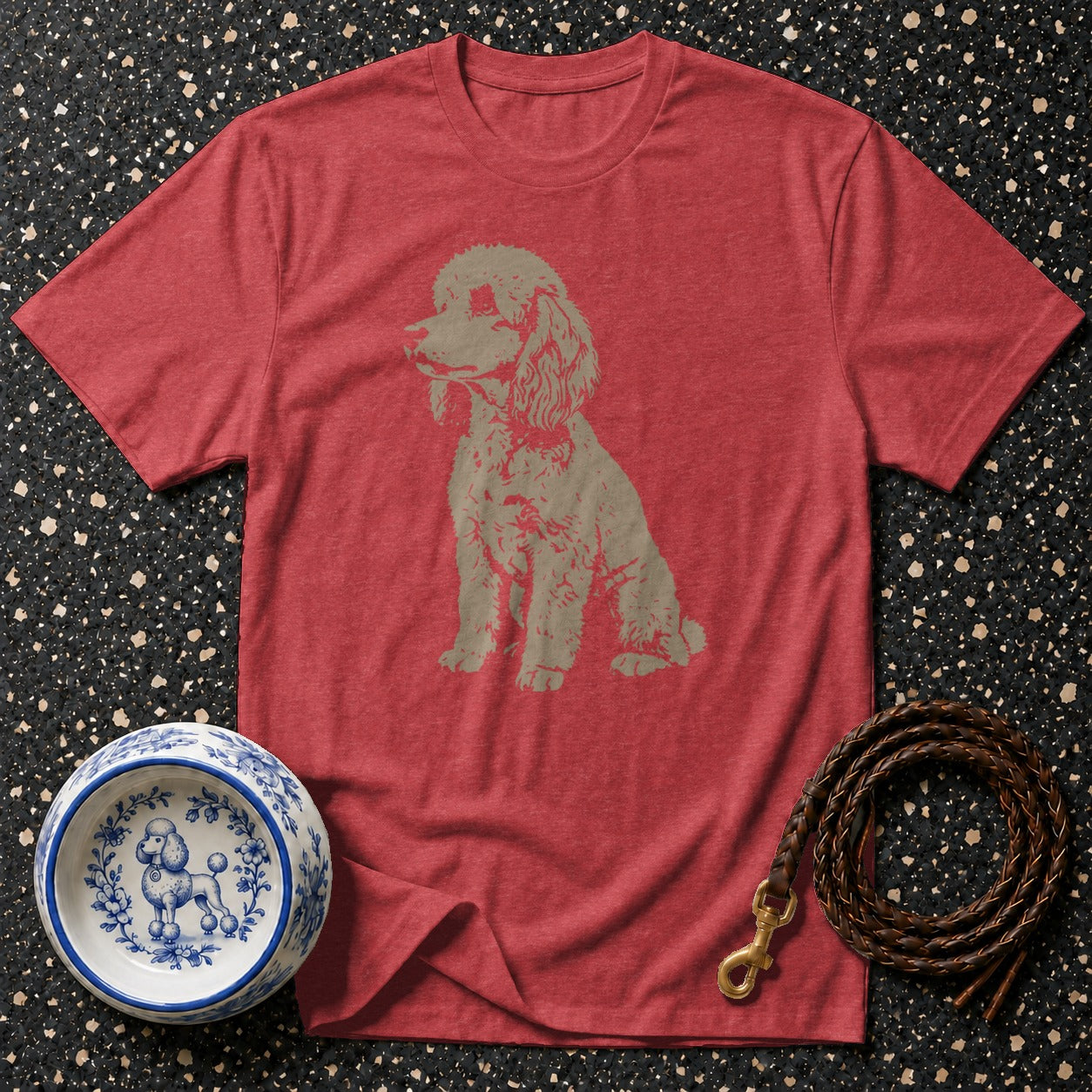 Red t-shirt with poodle graphic, blue and white dog bowl, and leather leash.