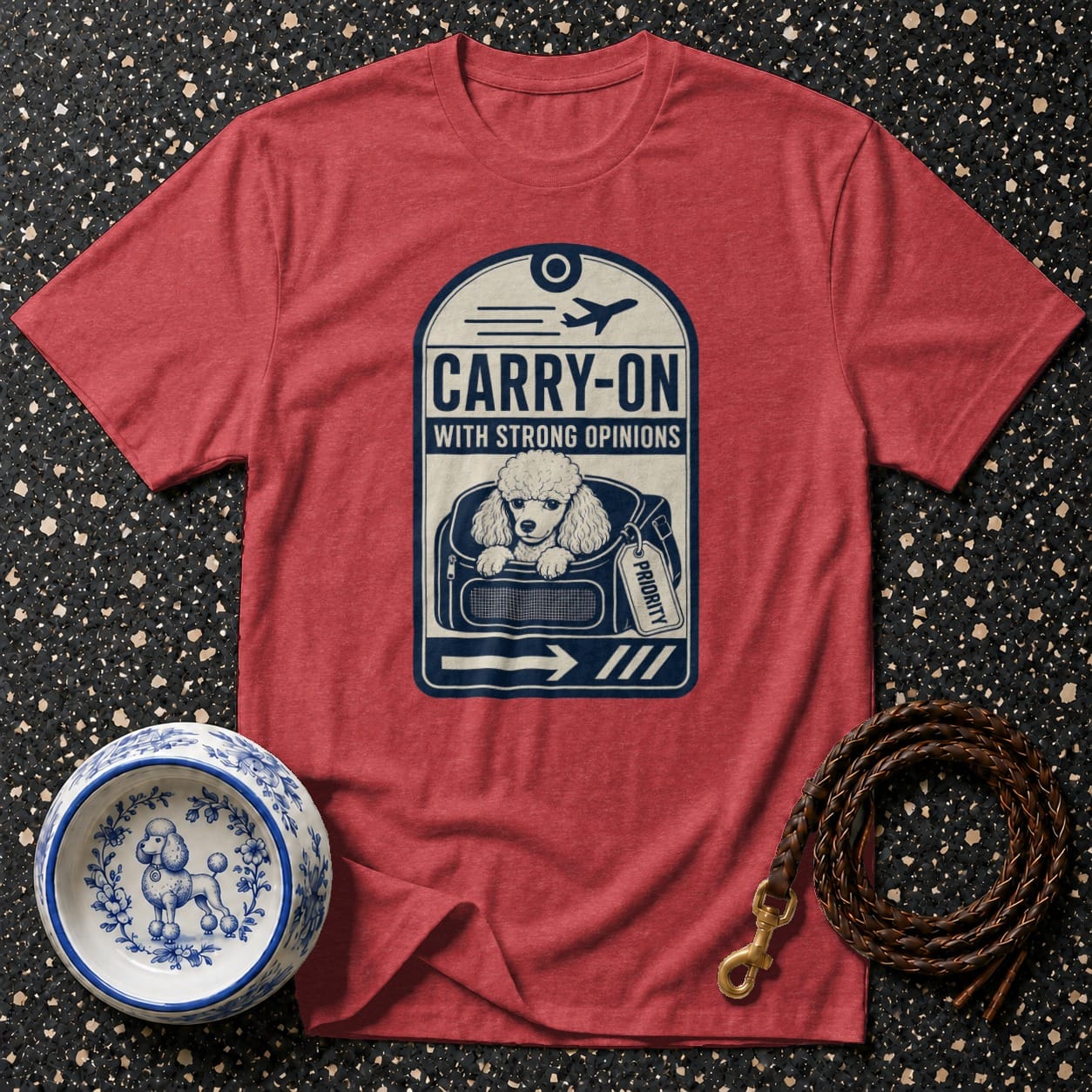 Red t-shirt with a graphic of a poodle in a carry-on bag, labeled "Carry-on with Strong Opinions."