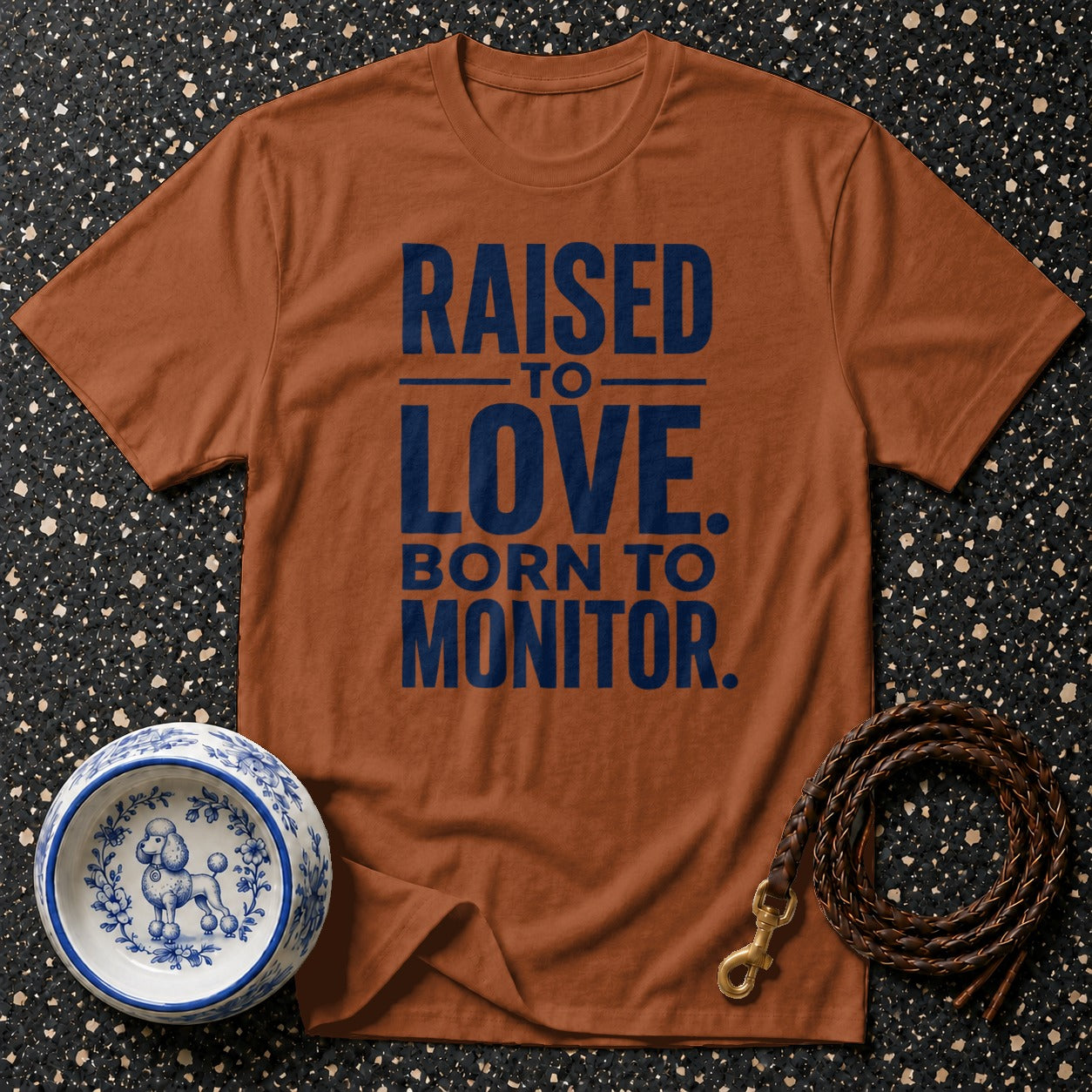 Brown t-shirt with "Raised to Love. Born to Monitor." text, dog bowl, and leash.