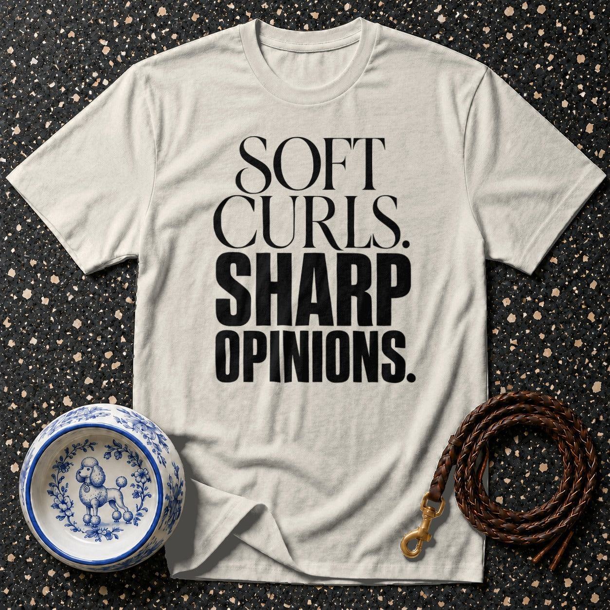 Cream t-shirt with black text "SOFT CURLS. SHARP OPINIONS." next to dog bowl and leash.