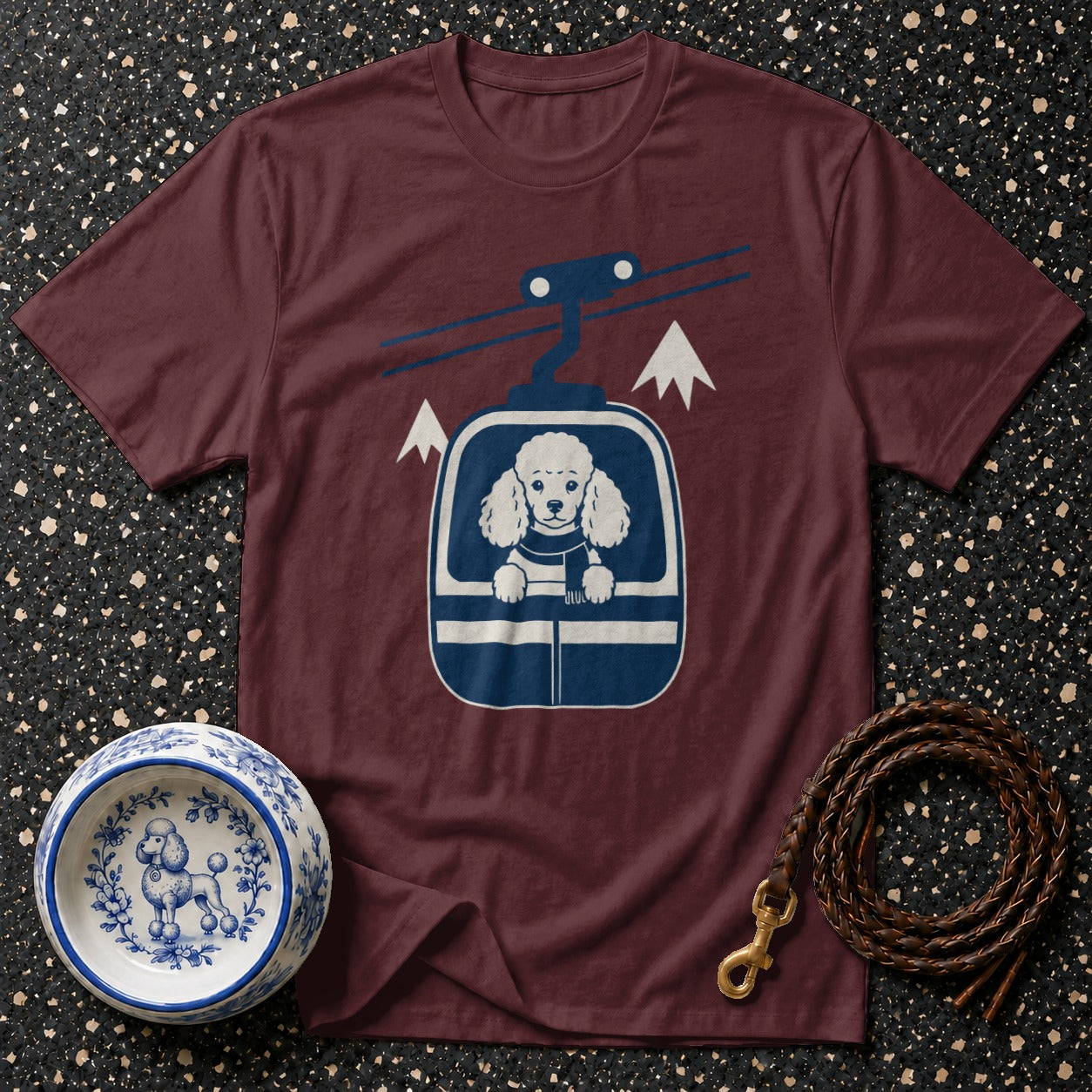T-shirt with graphic of poodle in ski lift and winter mountain scene.