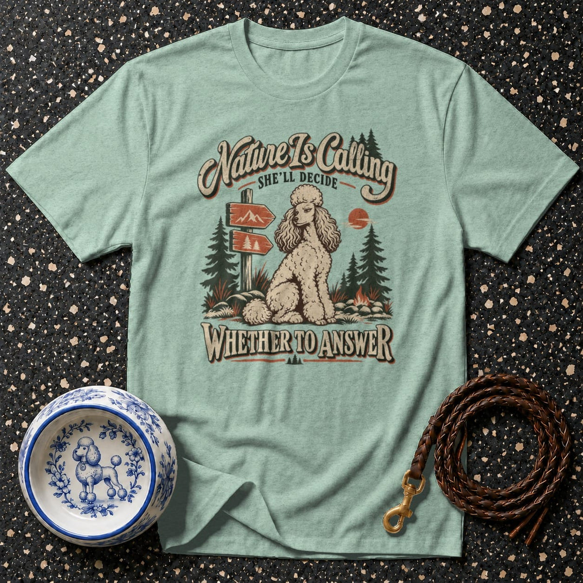 T-shirt graphic with poodle, mountains, and text "Nature Is Calling SHE'LL DECIDE WHETHER TO ANSWER".