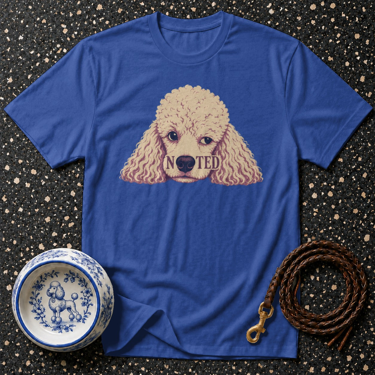Blue t-shirt with a poodle graphic featuring the word "NOTED" across its snout.