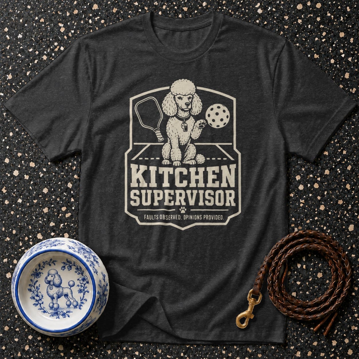 Dark t-shirt with graphic of a poodle holding a pickleball paddle and ball. Text reads "KITCHEN SUPERVISOR".