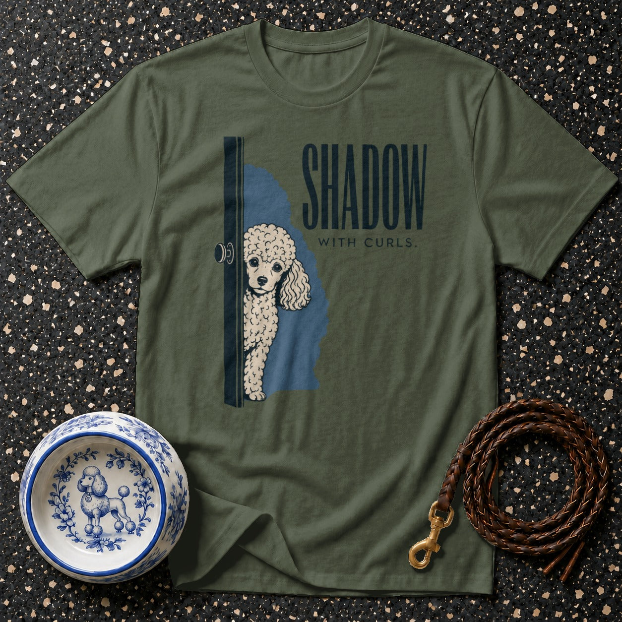 Olive green t-shirt with poodle peeking from behind a door and text "SHADOW WITH CURLS."