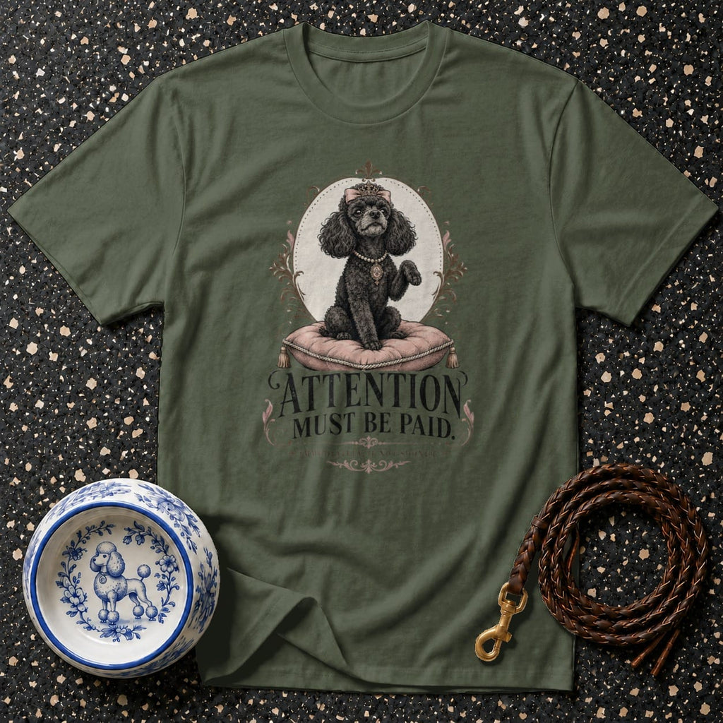 Green t-shirt with a black poodle wearing a crown and pearl necklace, sitting on a pillow.