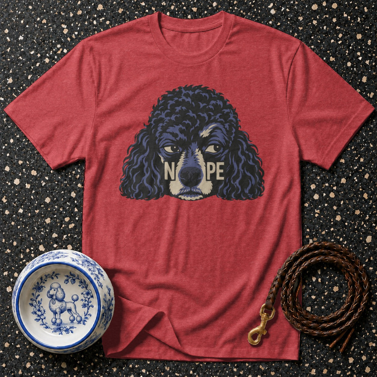 Red t-shirt with a poodle graphic saying "Nope", dog bowl, and leather leash.