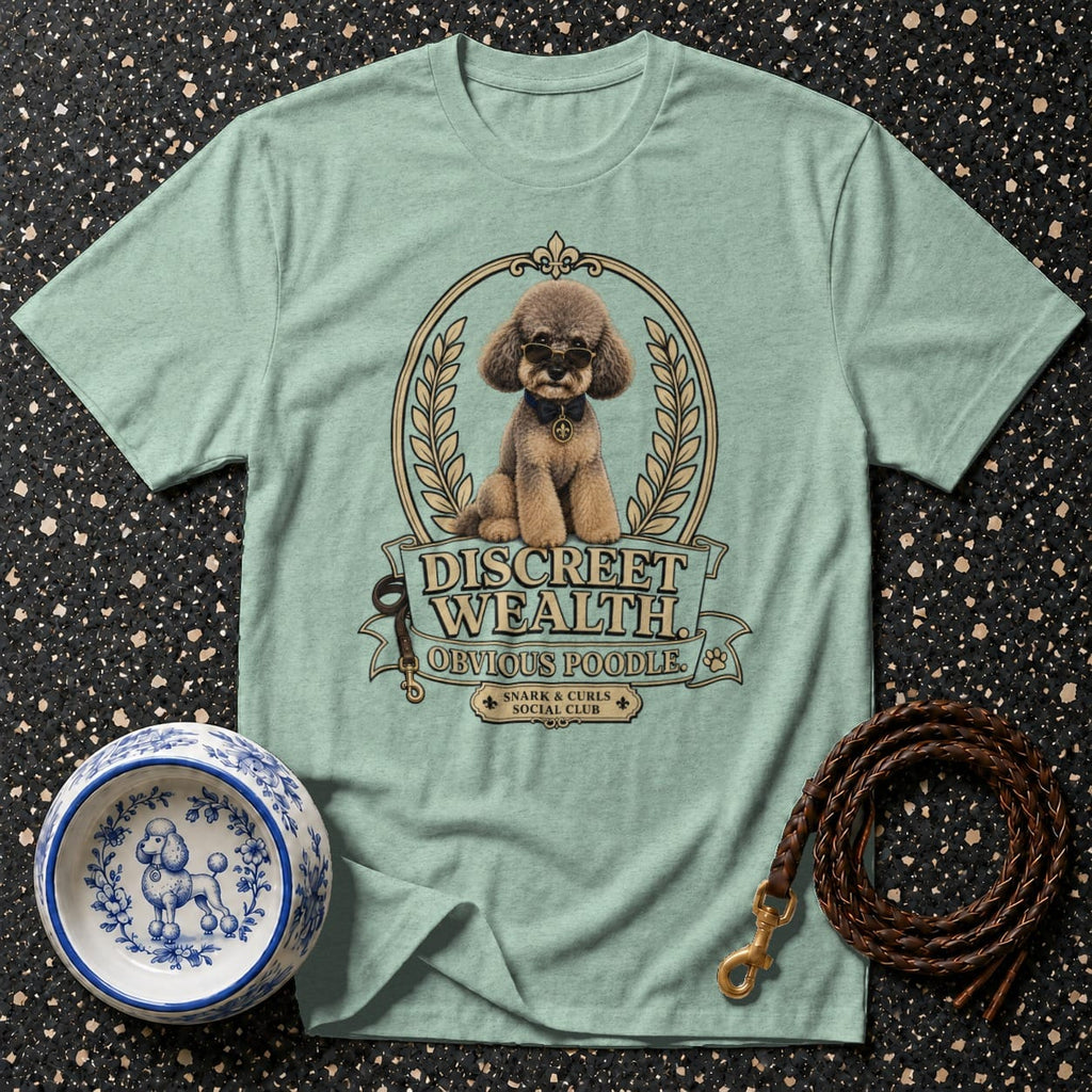 Light green t-shirt with a poodle graphic and text "DISCREET WEALTH OBVIOUS POODLE. SNARK & CURLS SOCIAL CLUB."