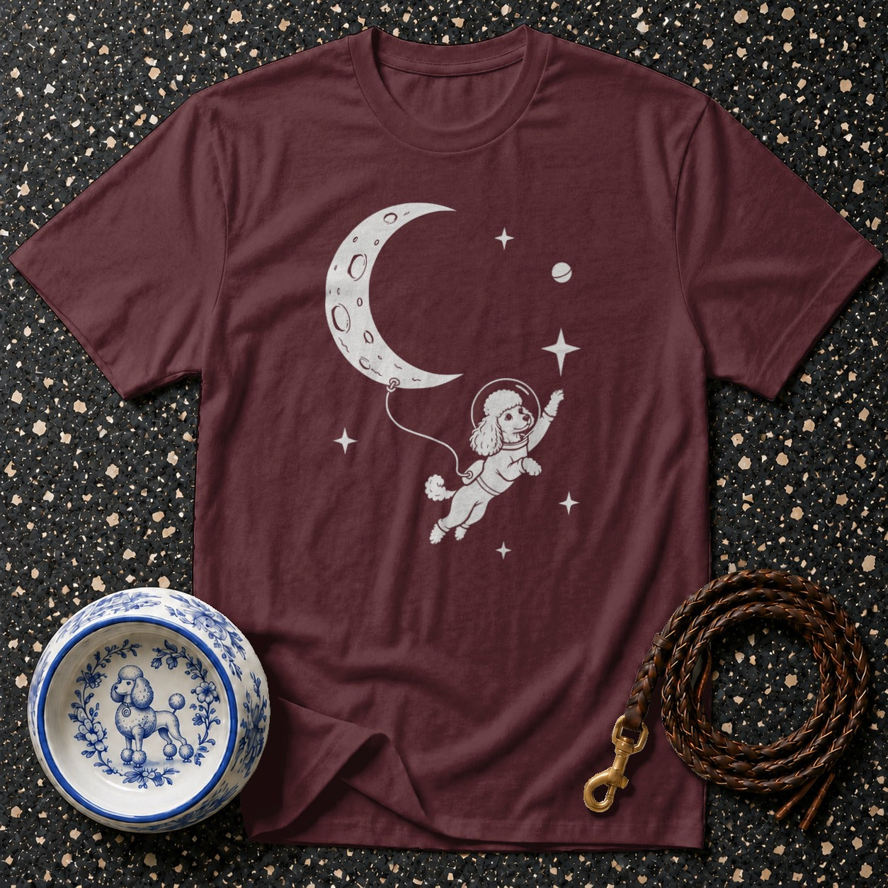 Maroon t-shirt with white graphic of a poodle in a spacesuit floating by the moon.