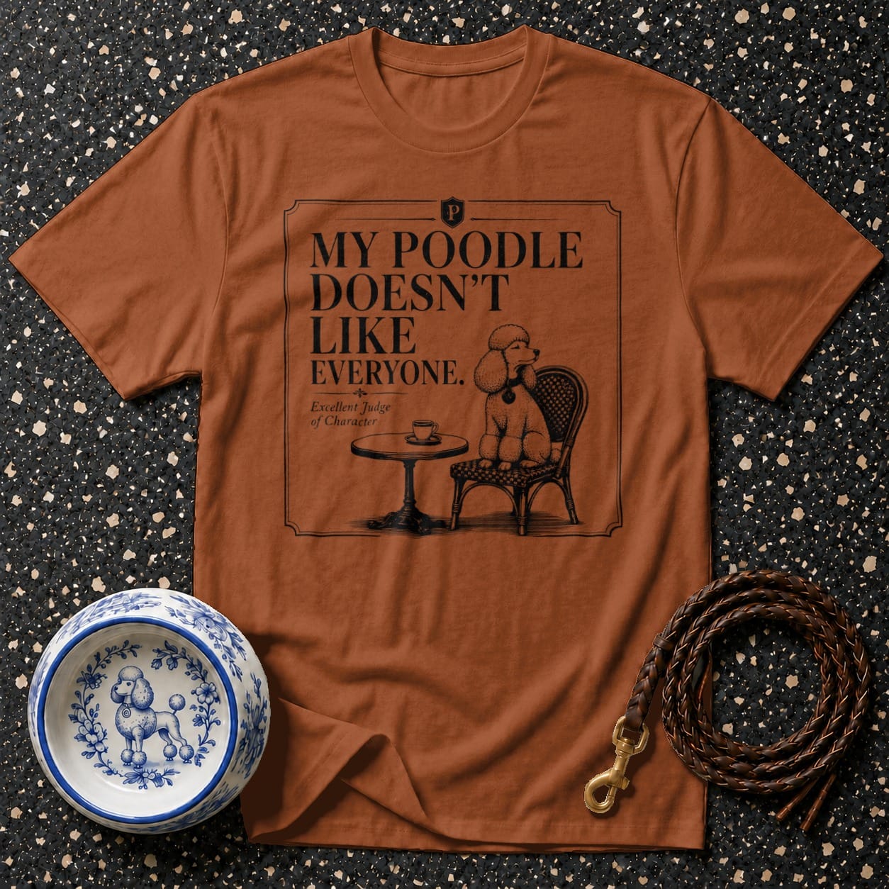 Brown t-shirt with "My poodle doesn't like everyone" graphic and poodle on chair.