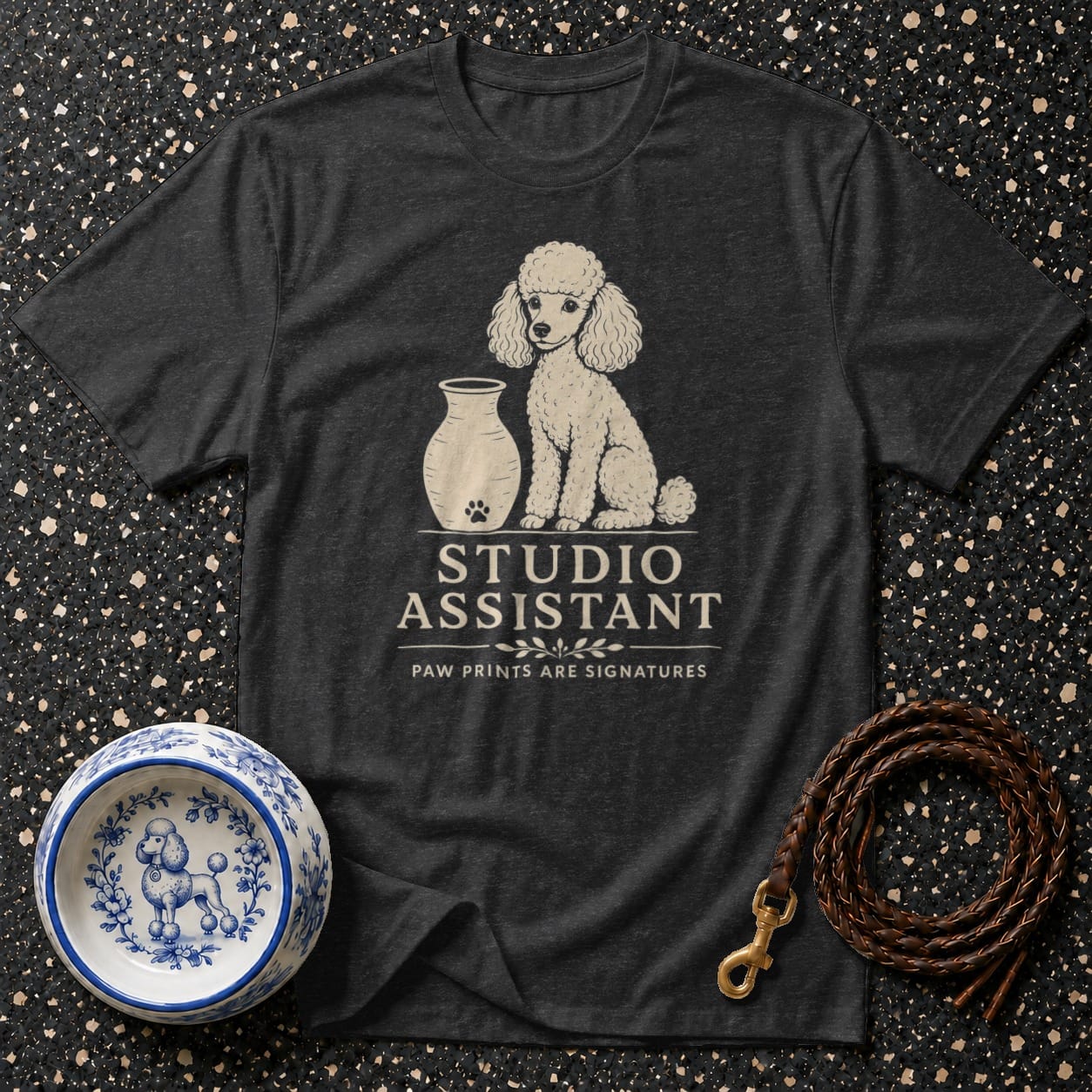 Dark t-shirt with white poodle graphic and "STUDIO ASSISTANT" text.