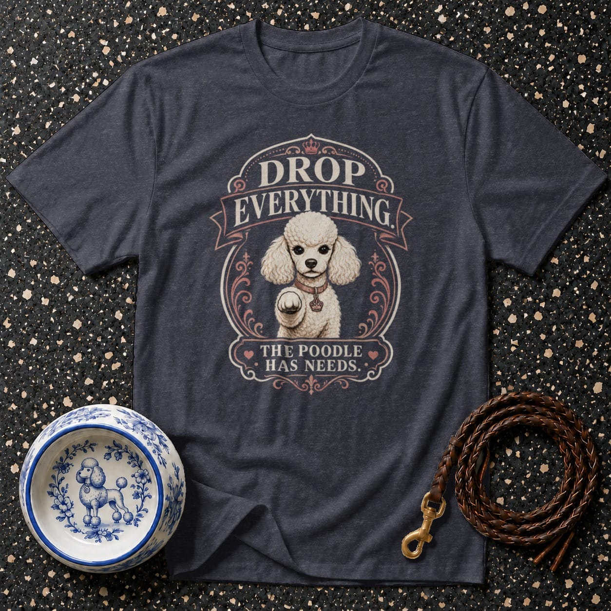 Dark t-shirt with poodle graphic and text "DROP EVERYTHING THE POODLE HAS NEEDS."