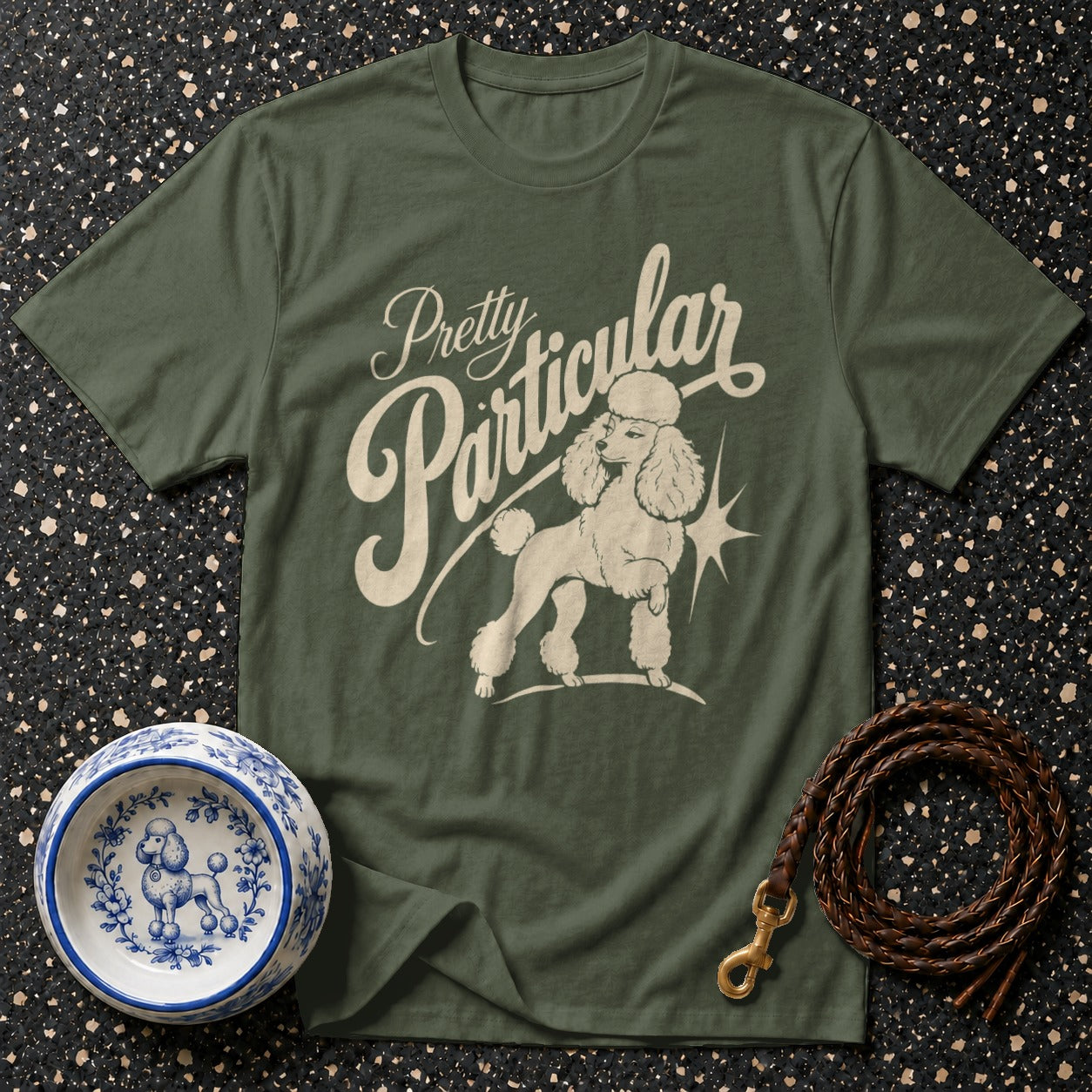 Olive green t-shirt with "Pretty Particular" and poodle graphic.