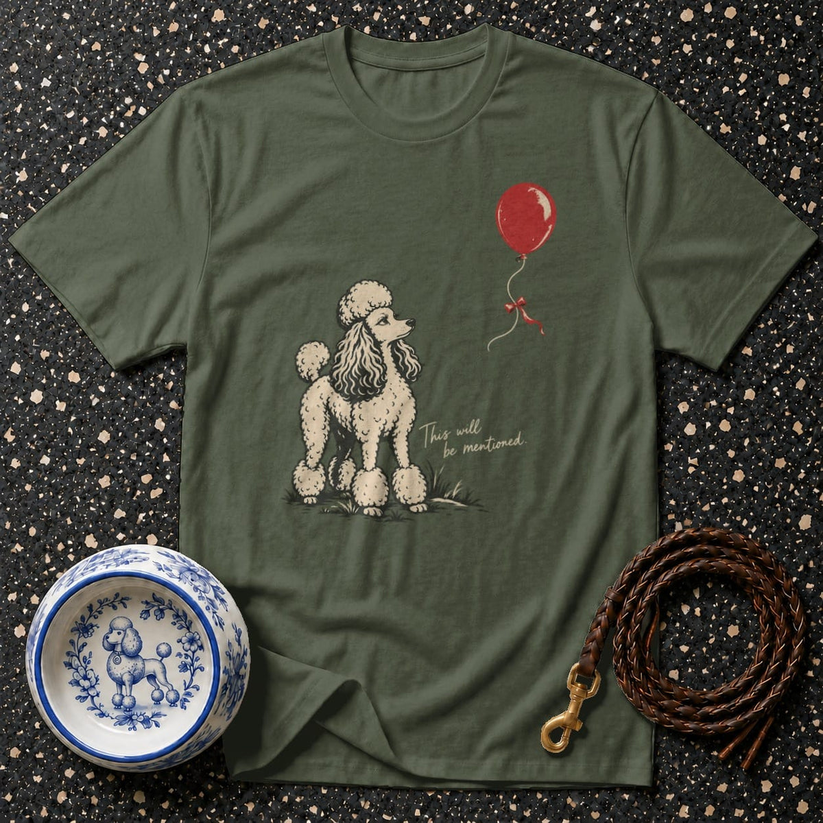 Olive green t-shirt with poodle illustration and red balloon. Text reads "This will be mentioned".