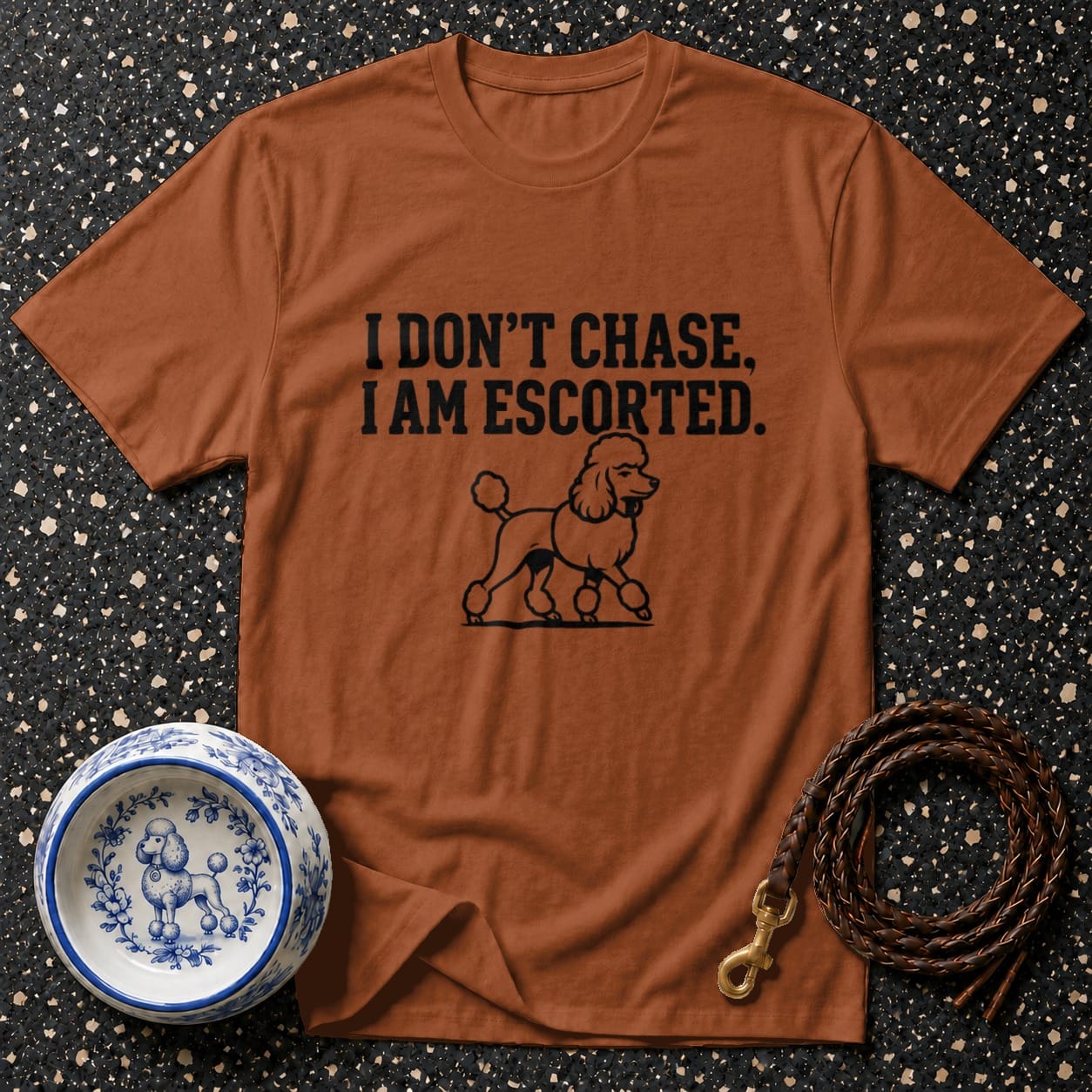 Brown t-shirt with poodle graphic and "I DON'T CHASE, I AM ESCORTED" text.