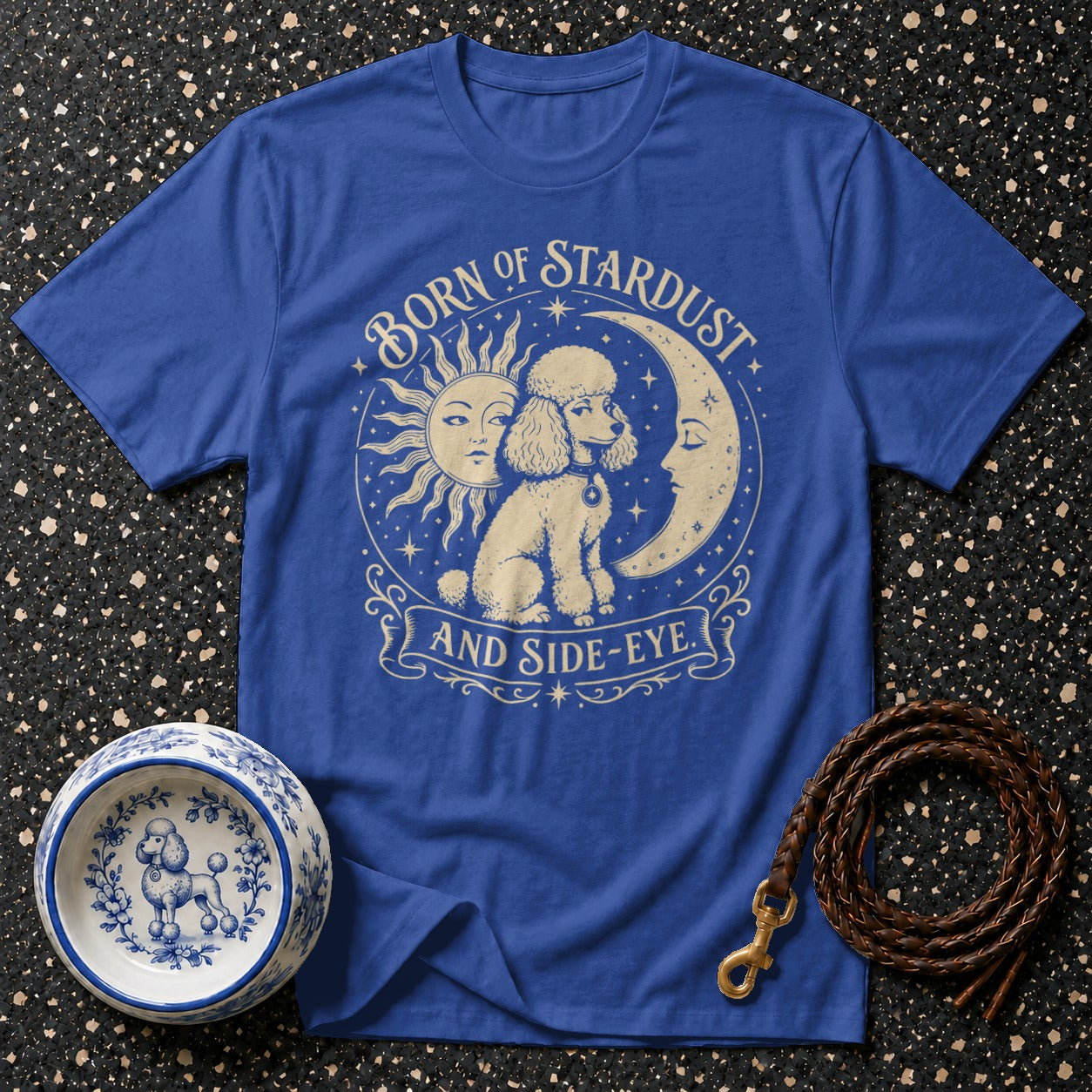 Blue t-shirt with a poodle between a sun and moon, reading "Born of Stardust and Side-Eye."