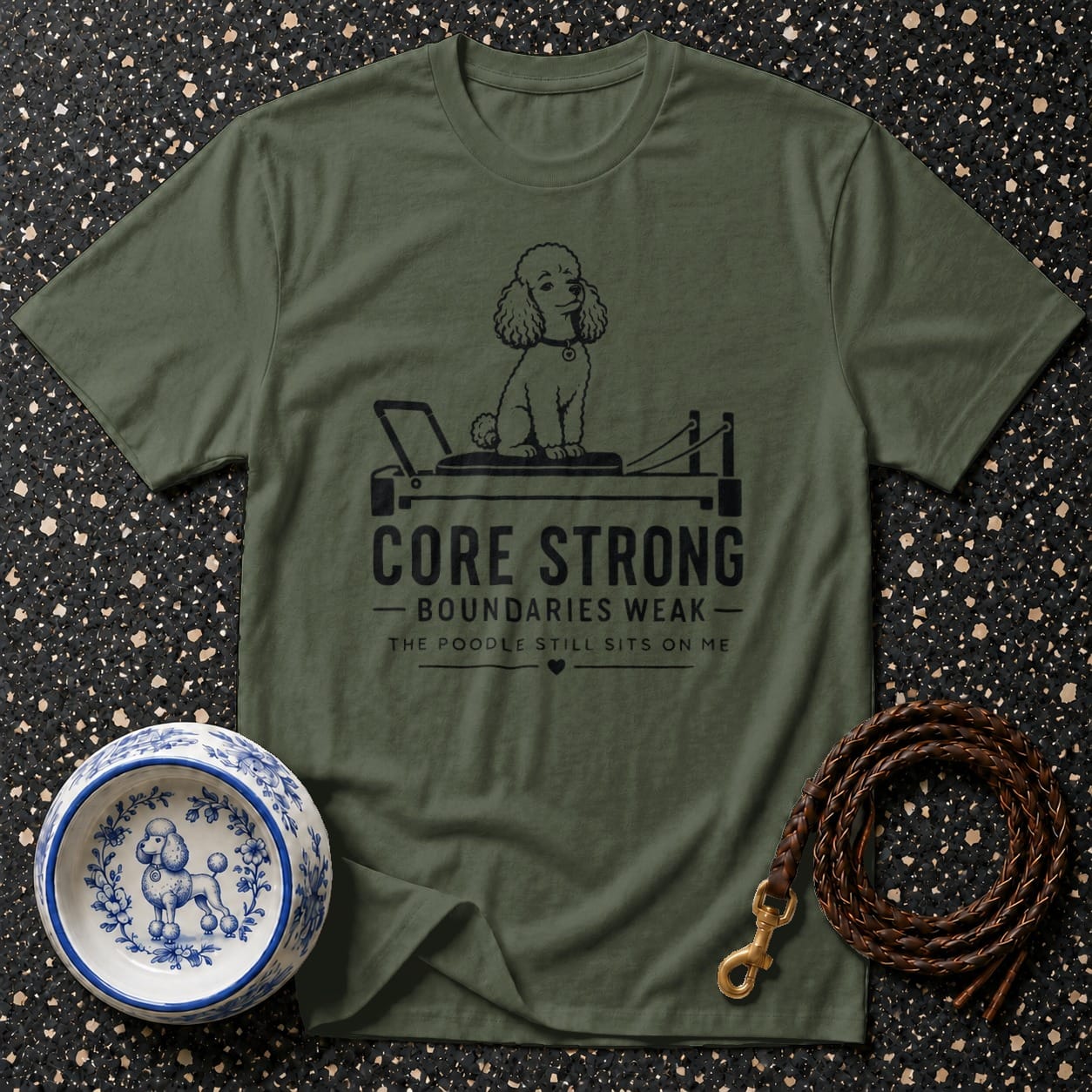 Olive green t-shirt with black print of a poodle on a reformer and text.