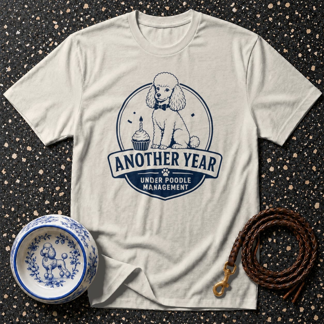 Cream t-shirt with dark blue poodle graphic: "Another year under poodle management."