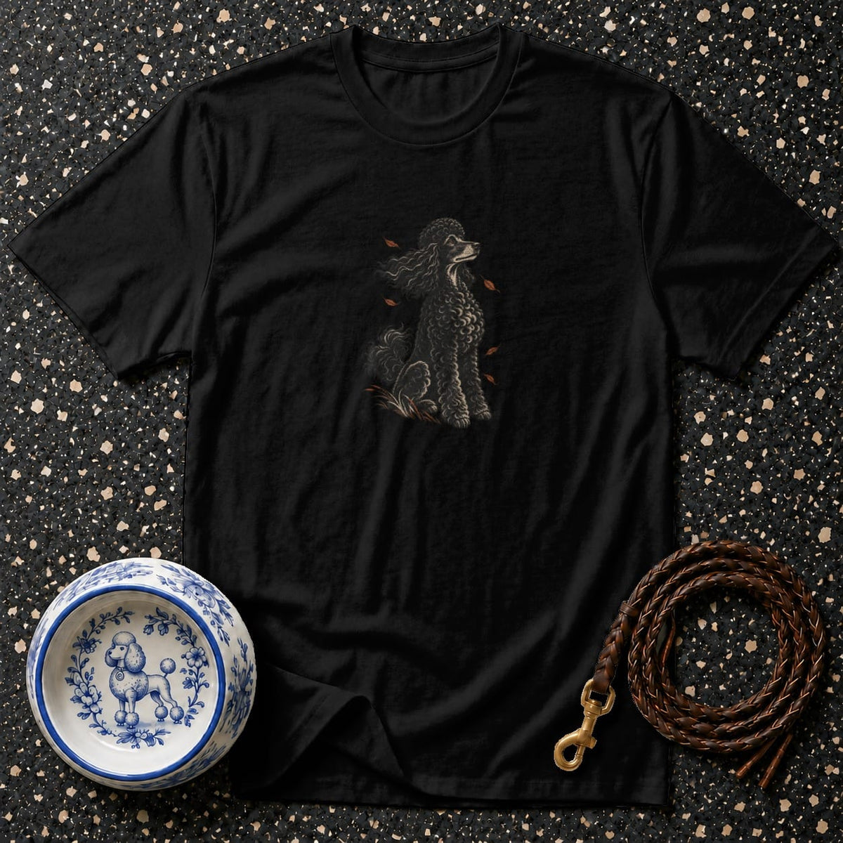 Black t-shirt with a sitting poodle graphic, next to a dog bowl and leash.