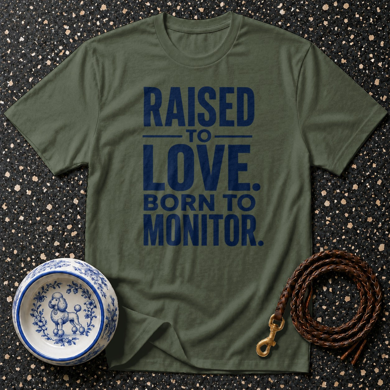 Olive green t-shirt with navy text reading "RAISED TO LOVE. BORN TO MONITOR."