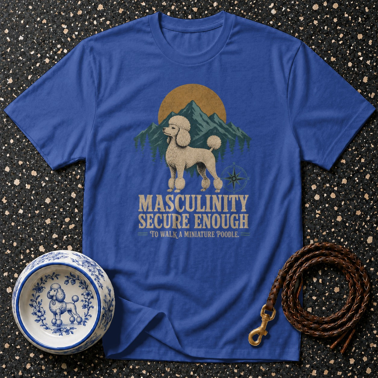 Blue t-shirt with a graphic of a poodle, mountains, and text "Masculinity Secure Enough".
