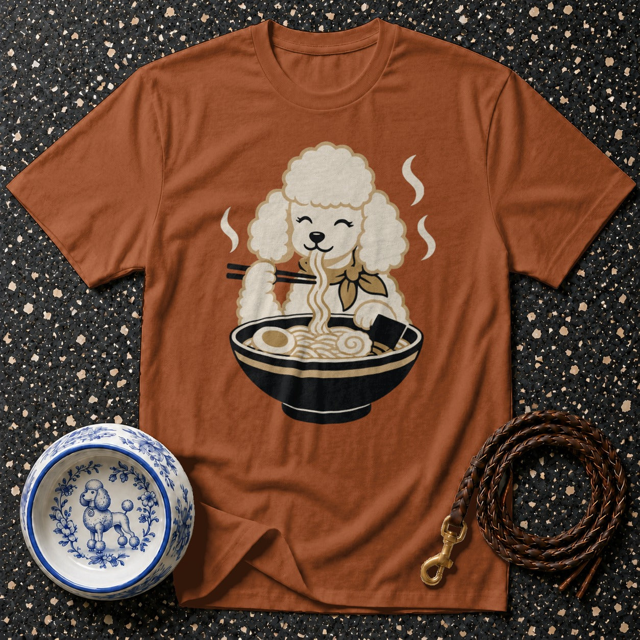 Brown t-shirt with a cartoon poodle eating ramen noodles from a bowl.