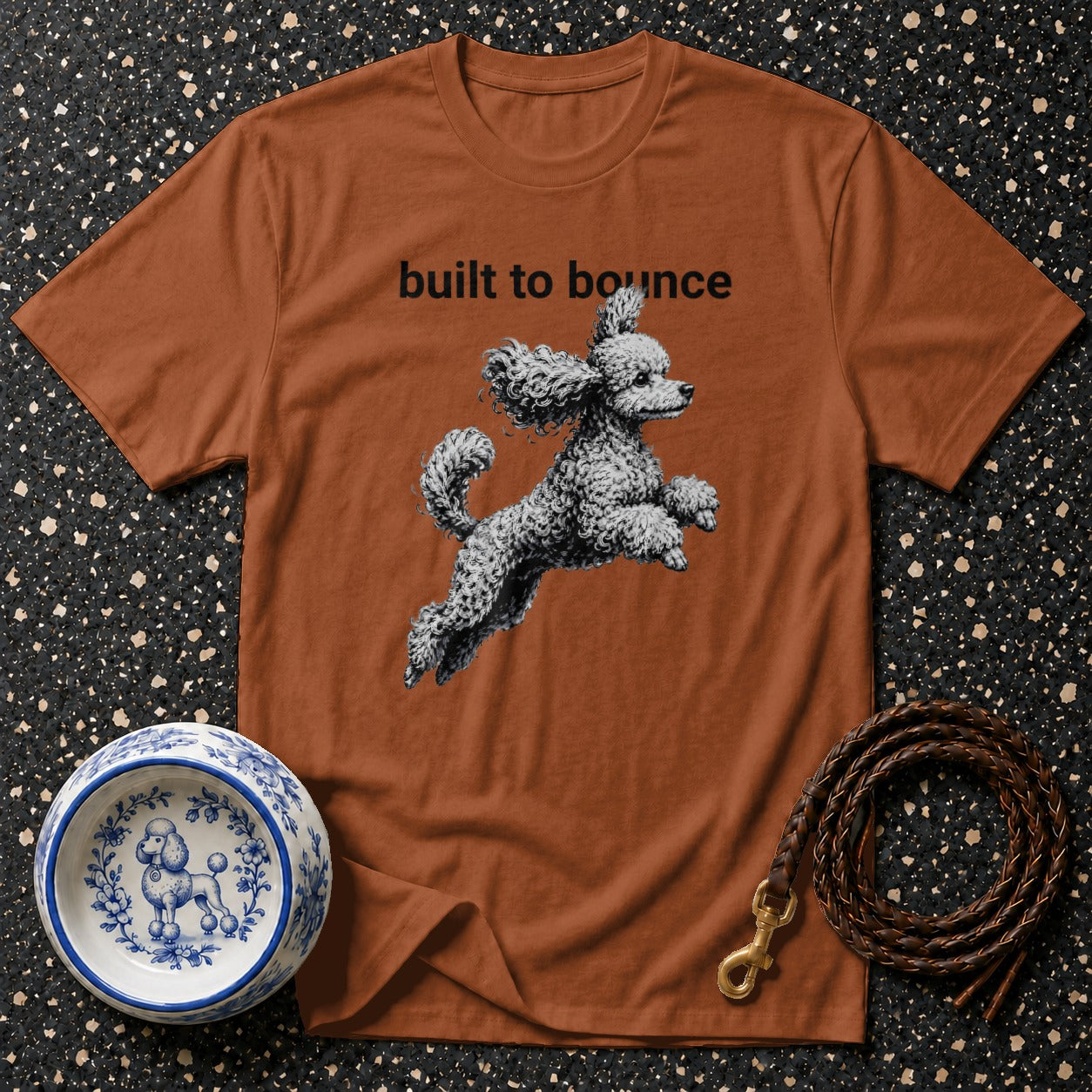 Brown t-shirt with "built to bounce" text and a poodle graphic.