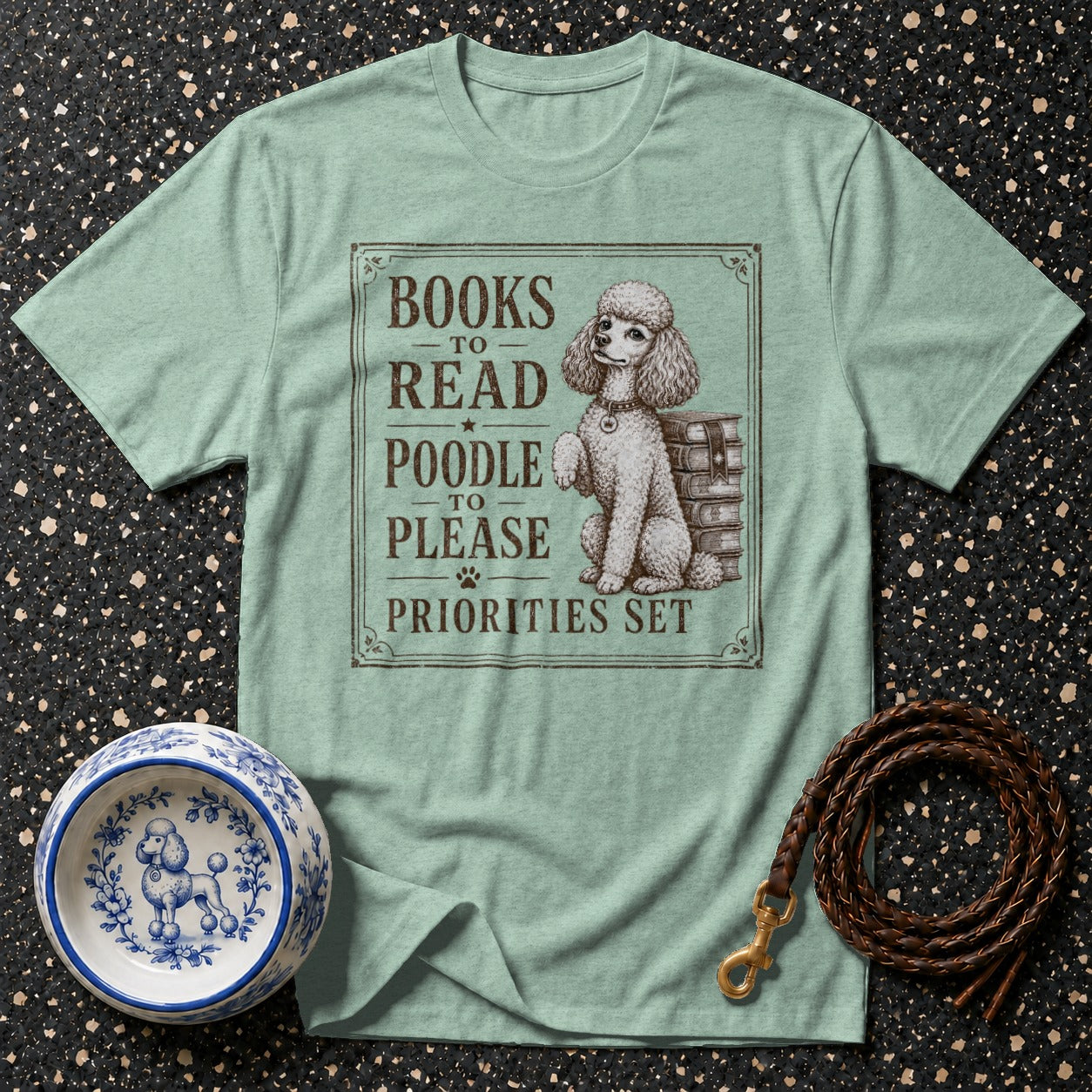 Light green t-shirt with a poodle and books graphic reading: "Books to read, poodle to please, priorities set."