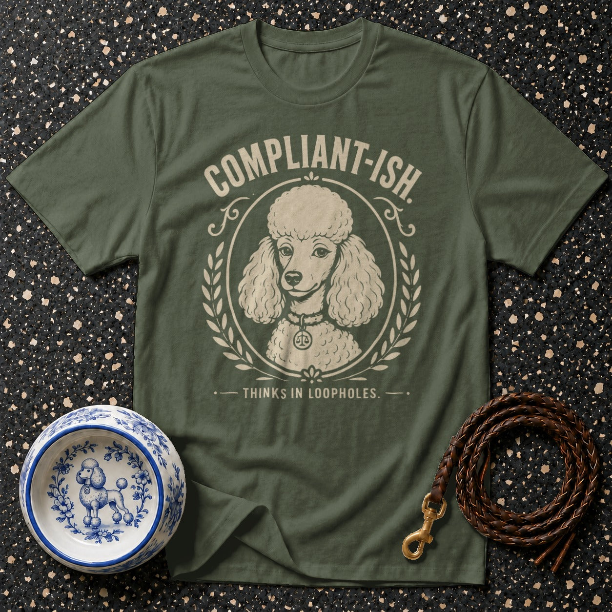 Green t-shirt with poodle graphic and text "COMPLIANT-ISH. THINKS IN LOOPHOLES."