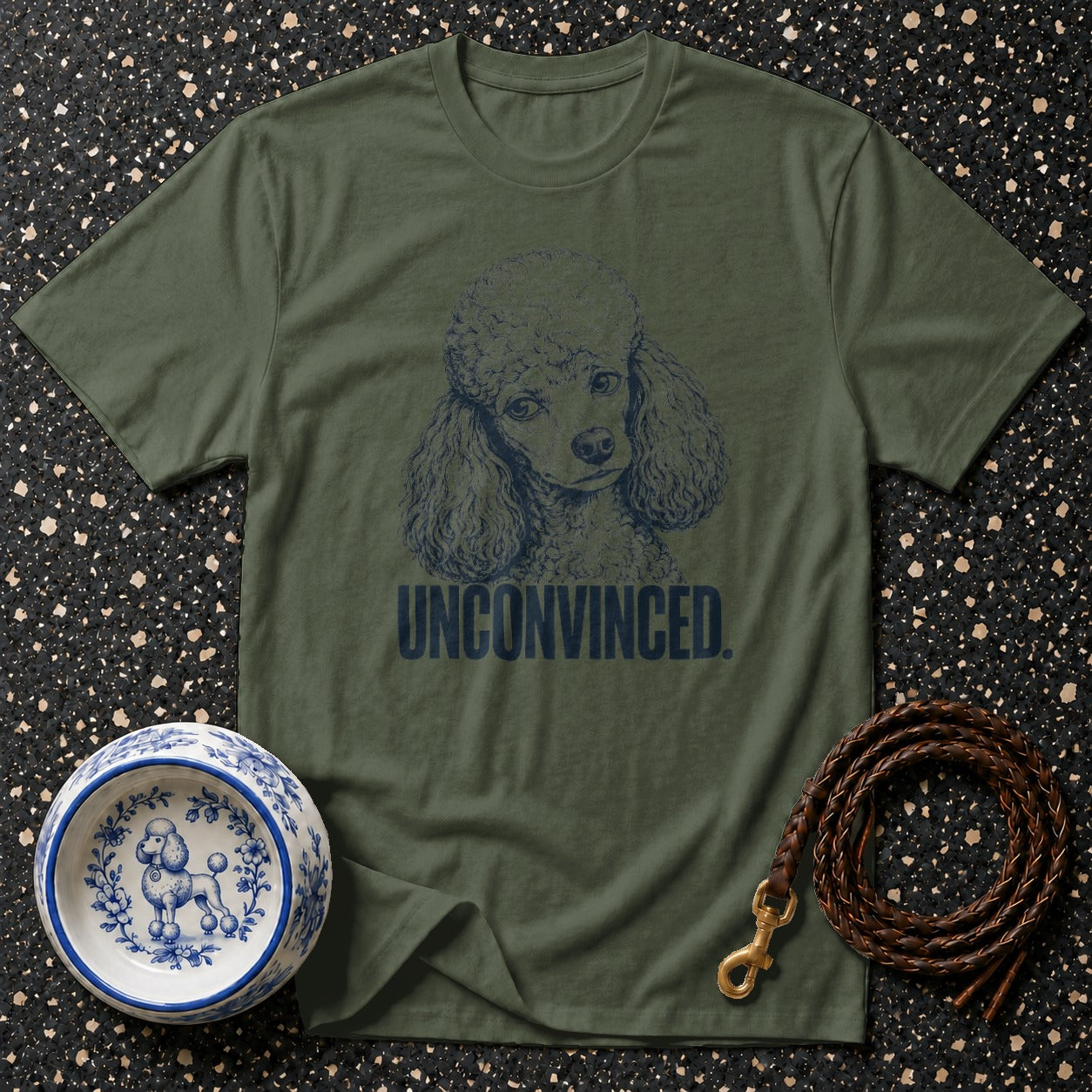 Olive green t-shirt with a navy poodle graphic and "UNCONVINCED" text.