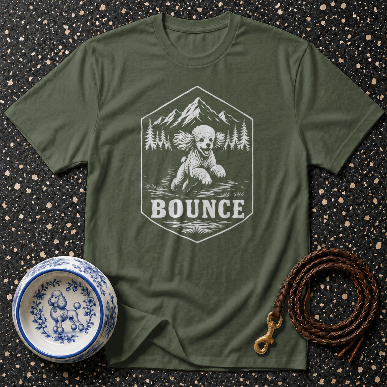Green t-shirt with a hexagon graphic of a dog, mountains, and trees, and the word "BOUNCE".