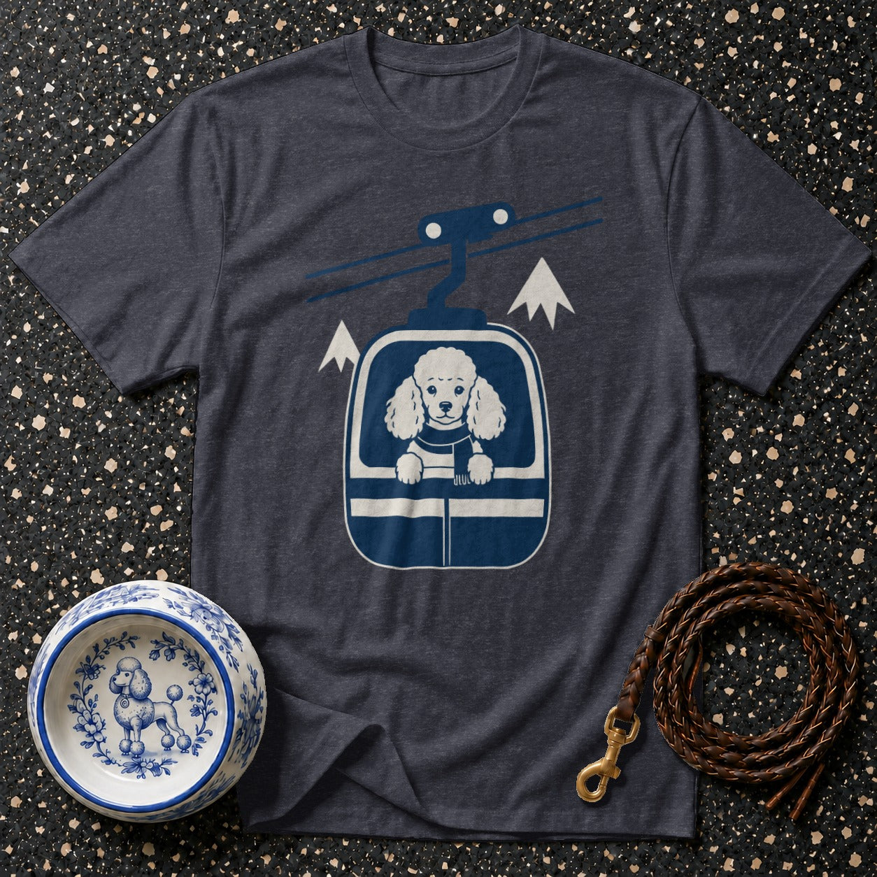 T-shirt with graphic of poodle in ski gondola with mountains and dog bowl.