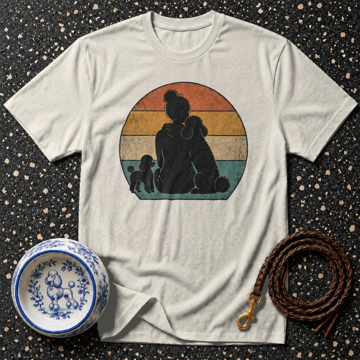 T-shirt with silhouette of person and two poodles against a vintage sunset.