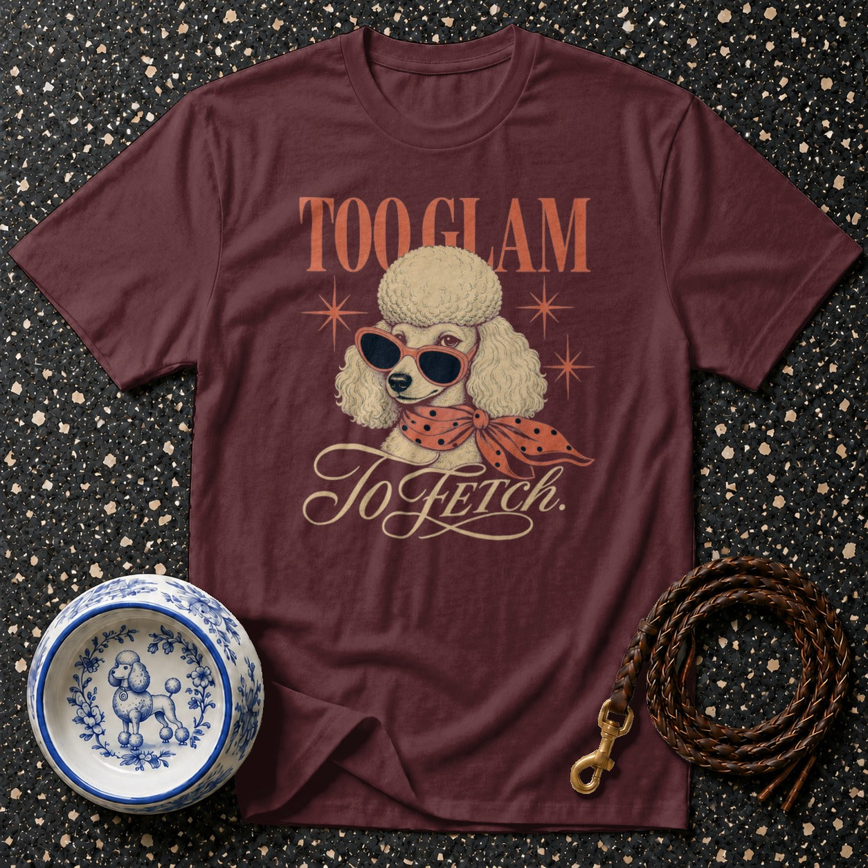 Maroon t-shirt with a poodle wearing sunglasses and a scarf, reading "Too Glam To Fetch."