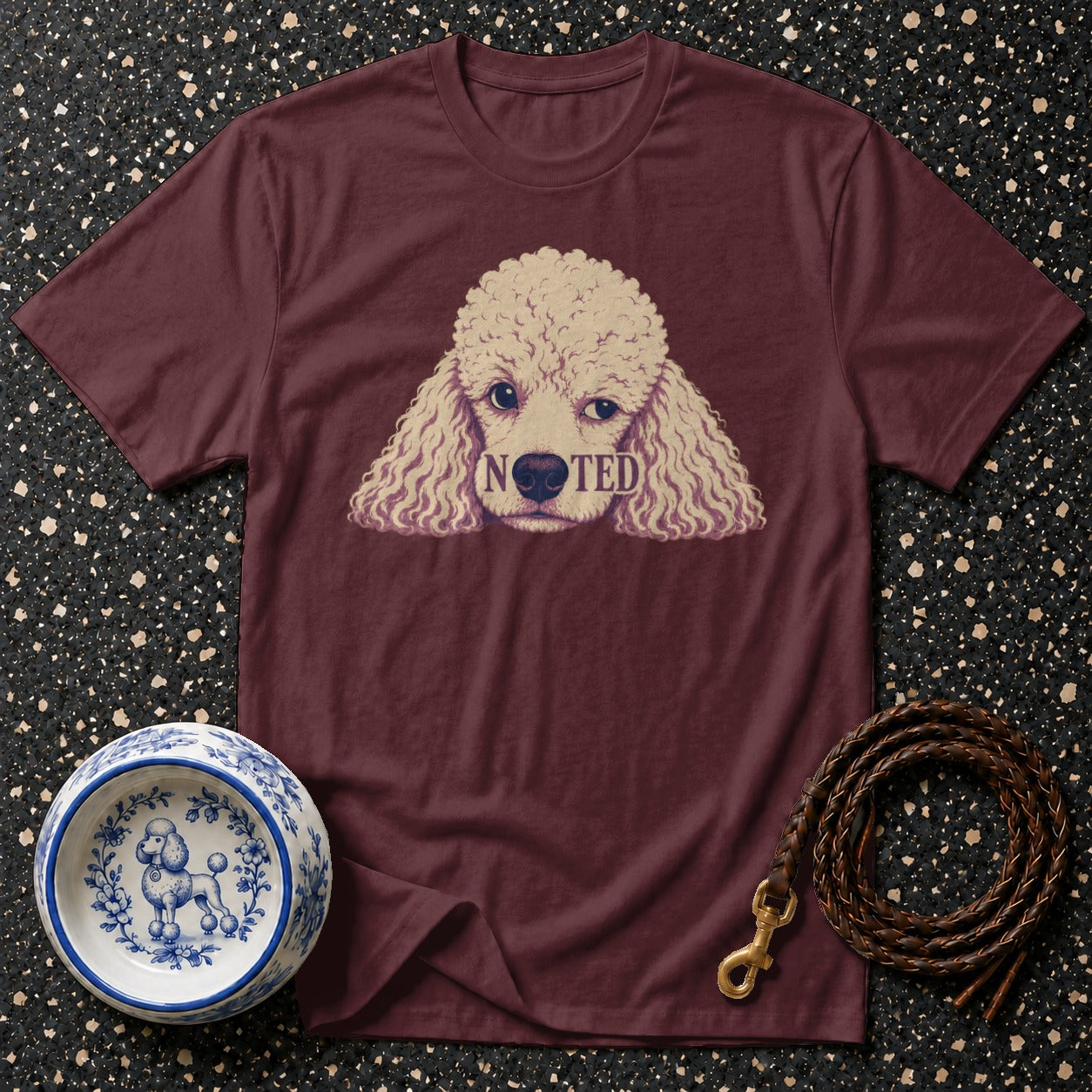 Maroon t-shirt with poodle graphic and the word "NOTED" on its face.