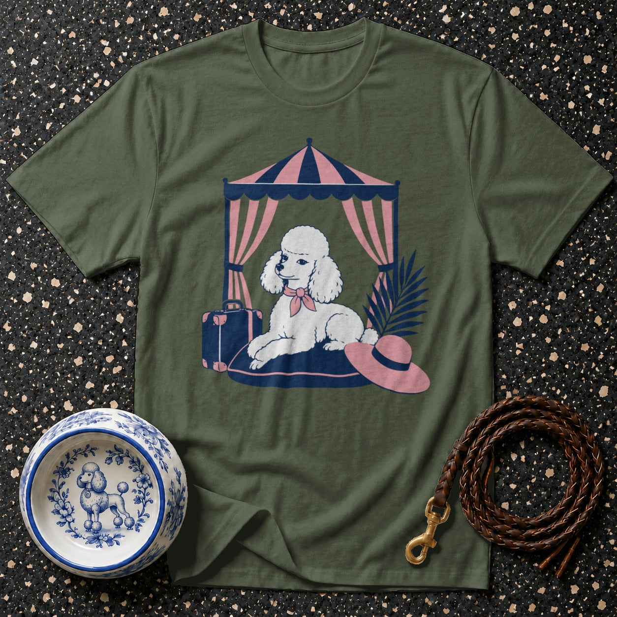 Green t-shirt graphic features a poodle under a tent with a suitcase and hat.