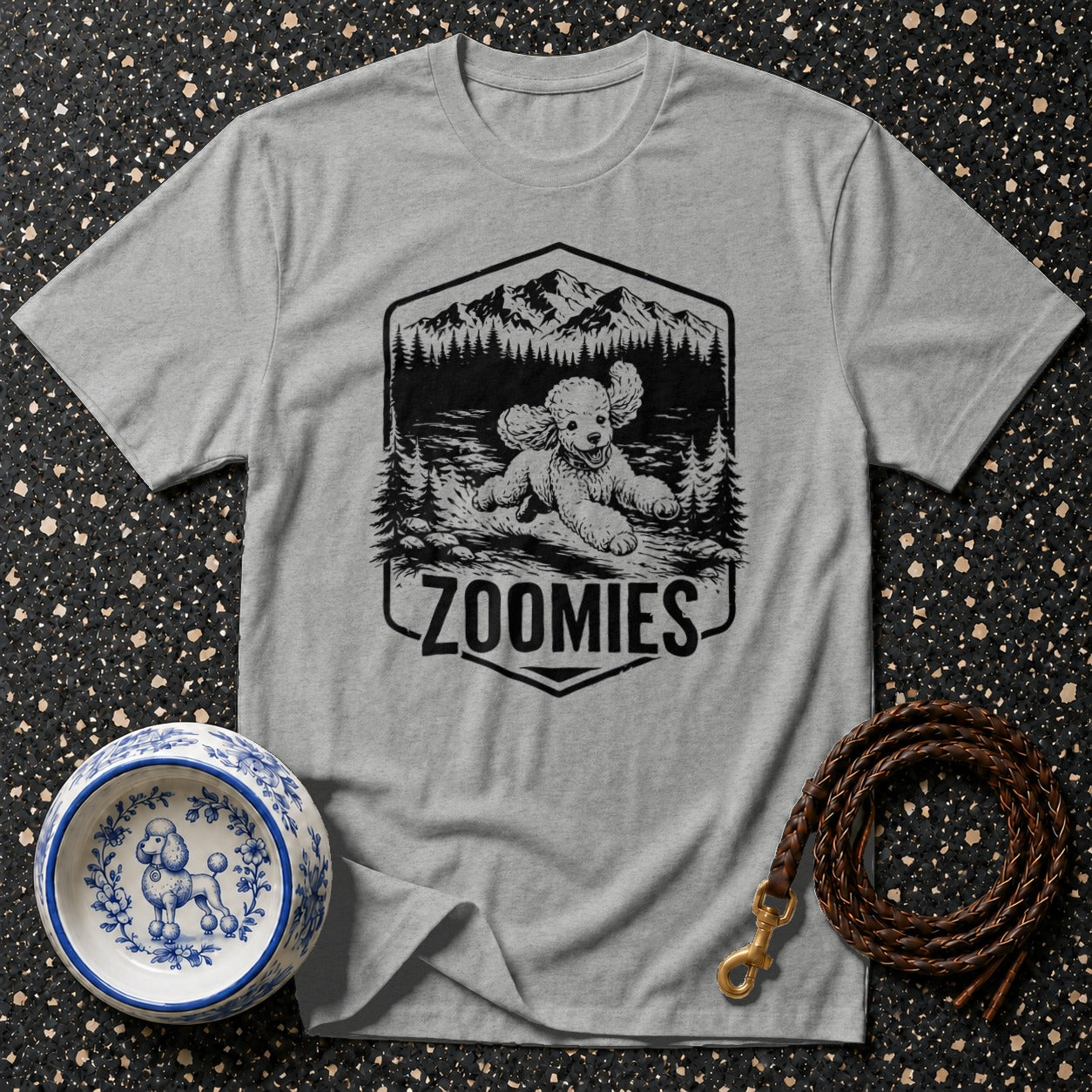 Grey t-shirt with black graphic of a poodle running in a forest scene, text "ZOOMIES".