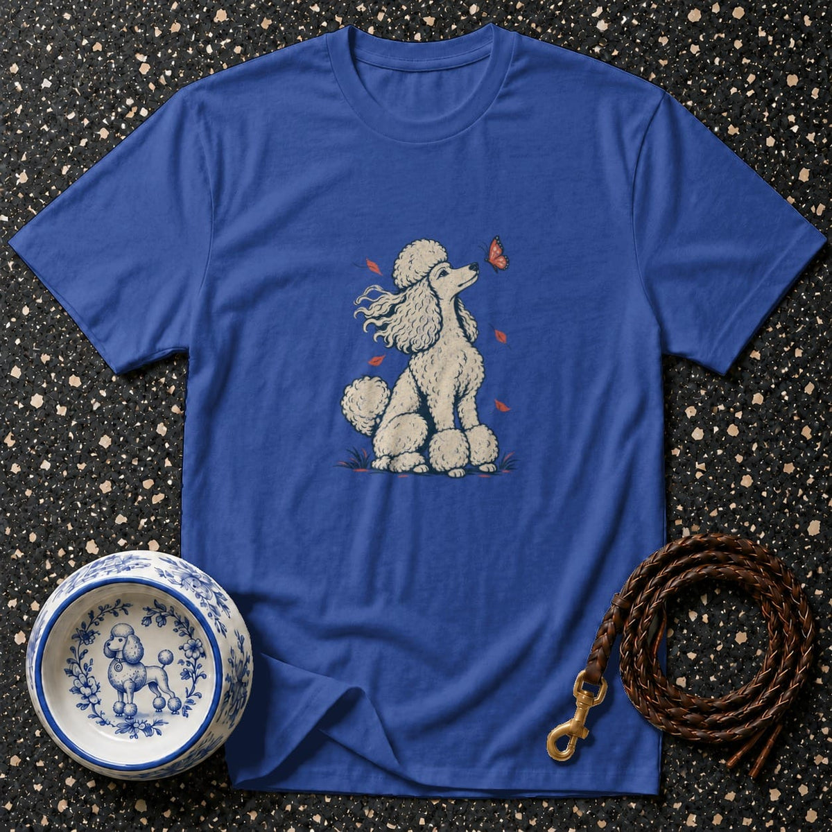 Blue t-shirt with a poodle and butterfly graphic, a decorative dog bowl, and a leather leash.