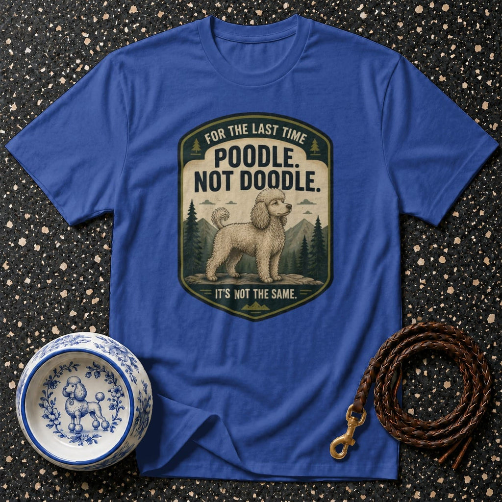 Blue t-shirt with a patch graphic of a poodle in a mountain scene reading "Poodle. Not Doodle."