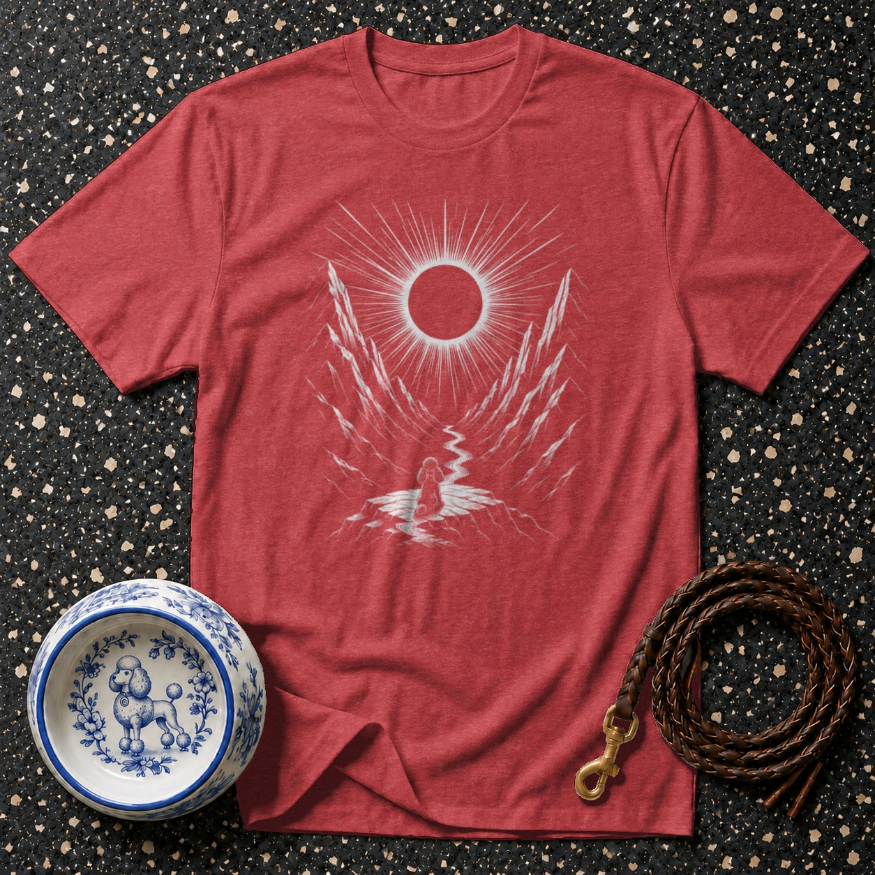 Red t-shirt with white graphic of sun, mountains, and person by a stream.
