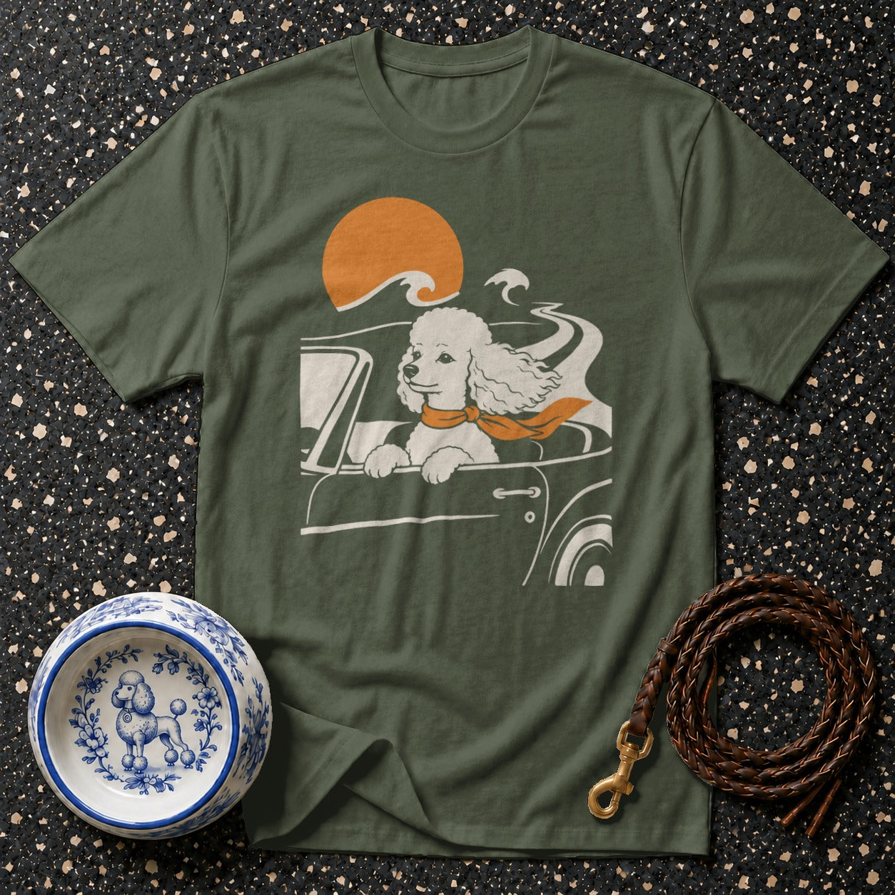 T-shirt with graphic of a poodle in a car with an orange scarf and sun.