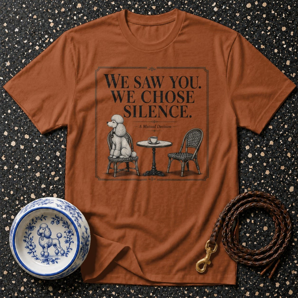 Brown t-shirt with graphic of poodle sitting at a table. Text reads "We saw you. We chose silence."