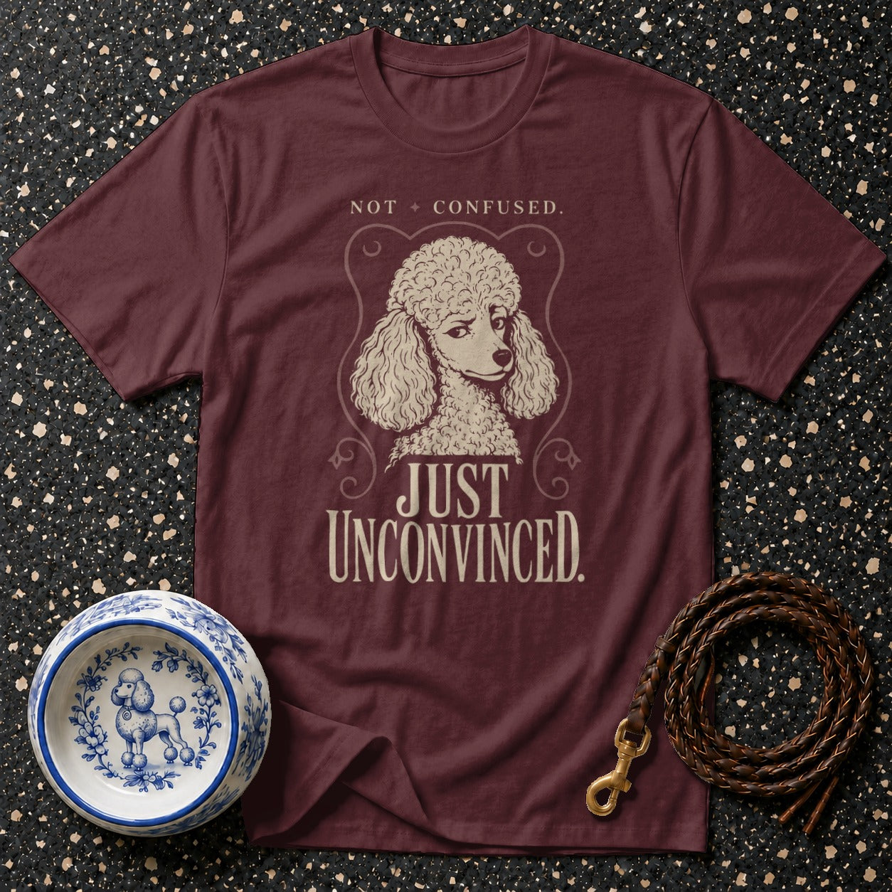 Maroon t-shirt with poodle illustration and text "NOT CONFUSED. JUST UNCONVINCED."