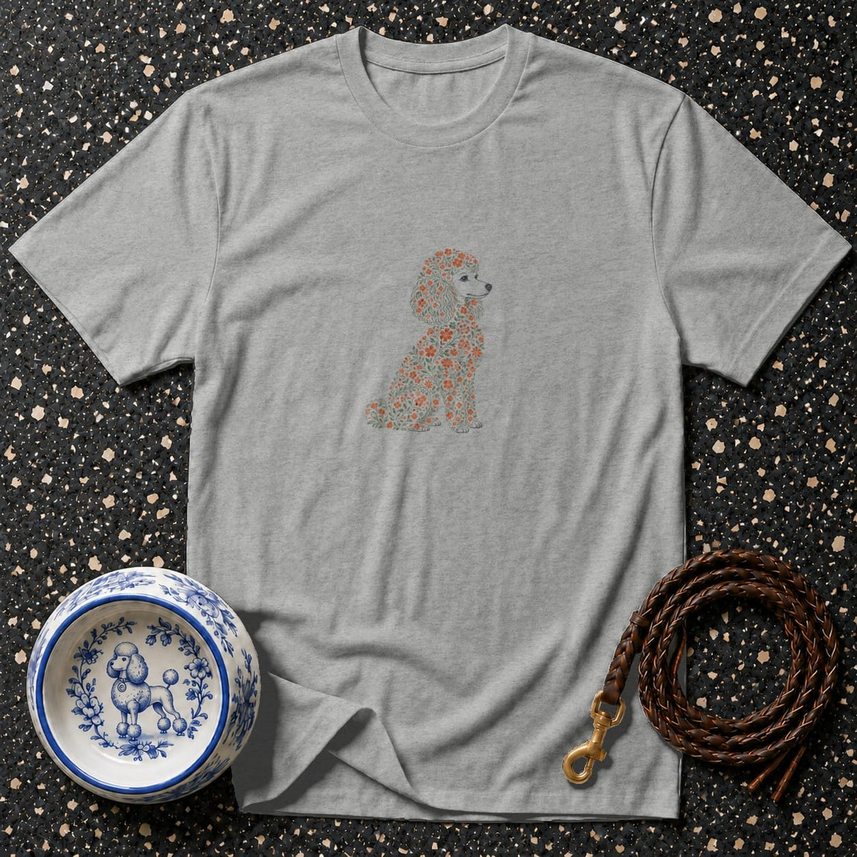 Gray t-shirt with floral poodle graphic, blue and white dog bowl, and leather leash.